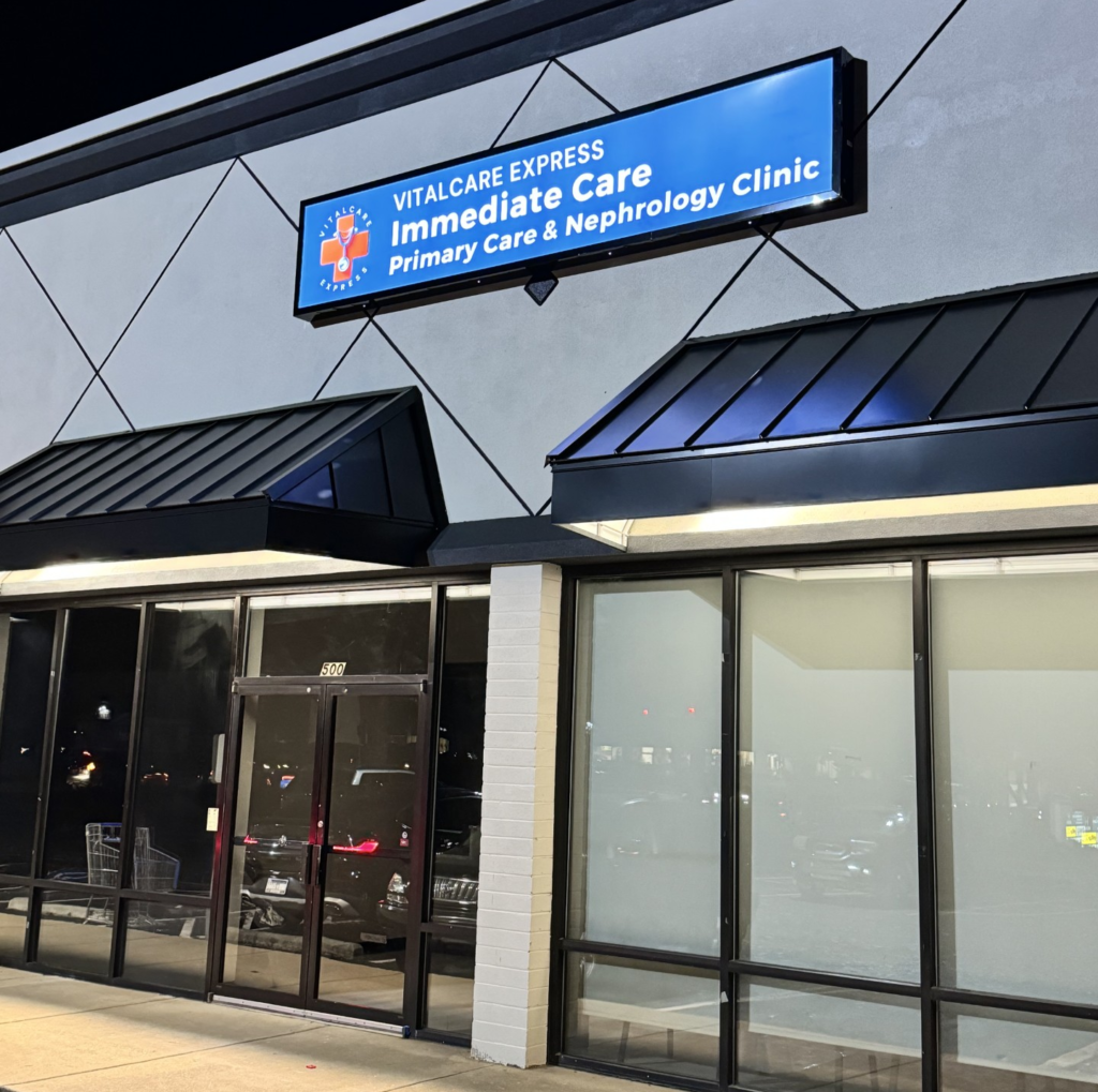 Exterior of VitalCare Express clinic showing illuminated signage for immediate care and primary care services at night