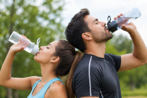People drinking water outdoors as part of summer health tips to stay hydrated in hot weather.